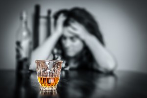 Alcohol addiction : Portrait of a lonely and desperate drunk hispanic woman (image focused on her drink)