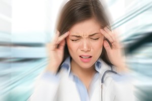 Migraine and headache people - Doctor stressed. Woman Nurse / doctor with migraine headache overworked and stressed. Health care professional in lab coat wearing stethoscope at hospital.