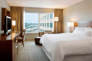 Room at the Westin Pittsburgh: Bed with white comforter and a big window that looks out at a yellow bridge over a river