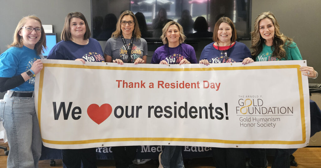 Row of six people holding a banner that says Thank a Resident Day, We (heart) our residents!